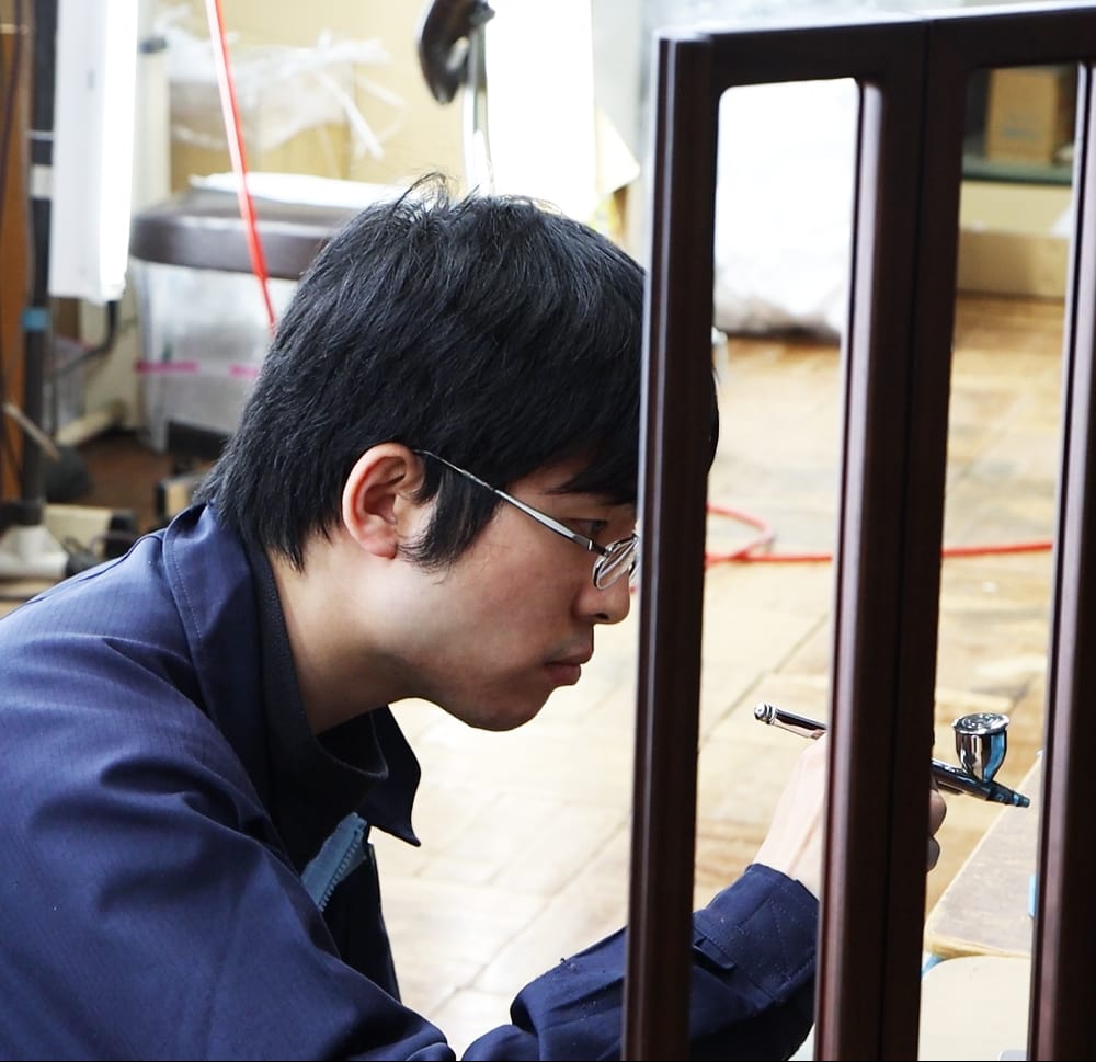 職人がお仏壇への塗装作業をしているイメージ